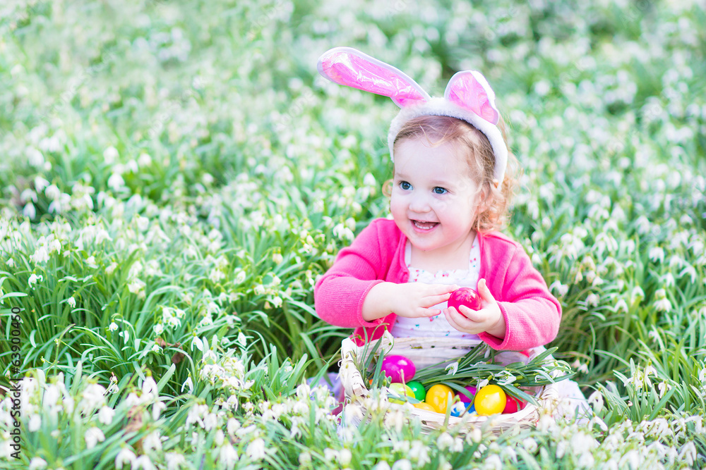 Beautiful toddler girl in bunny ears playing with Easter eggss Beautiful toddler girl in bunny ears playing with Easter eggss