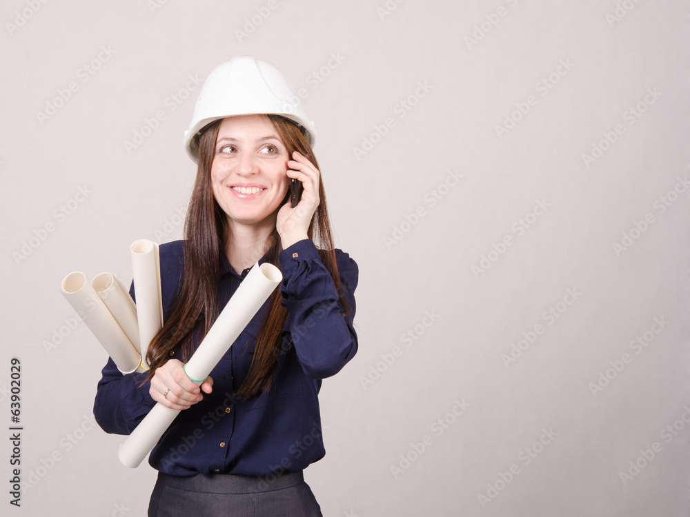 Young woman talking on phone with blueprints in hand Young woman talking on phone with blueprints in hand