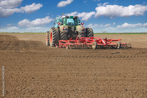 Agricultural tractor cultivating field, preparing for sowing