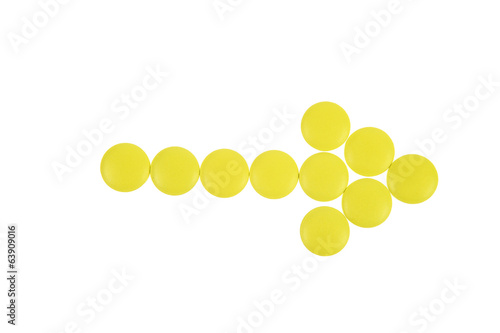 Arrow of yellow pills on white background