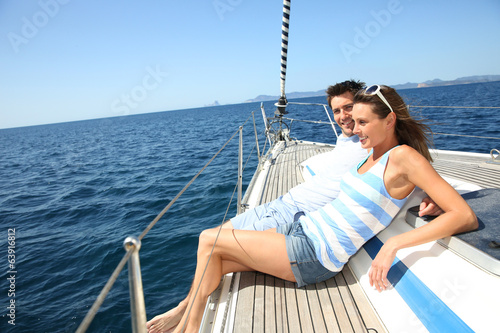 Cheerful couple relaxing on sailboat while navigating