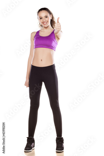 young sporty girl showing thumb up on white