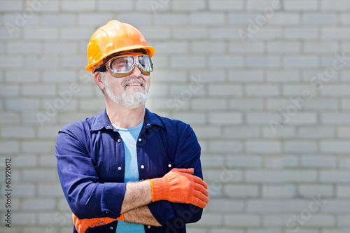 Portrait of happy seniorman with hard hat Posing with crossed ar photo