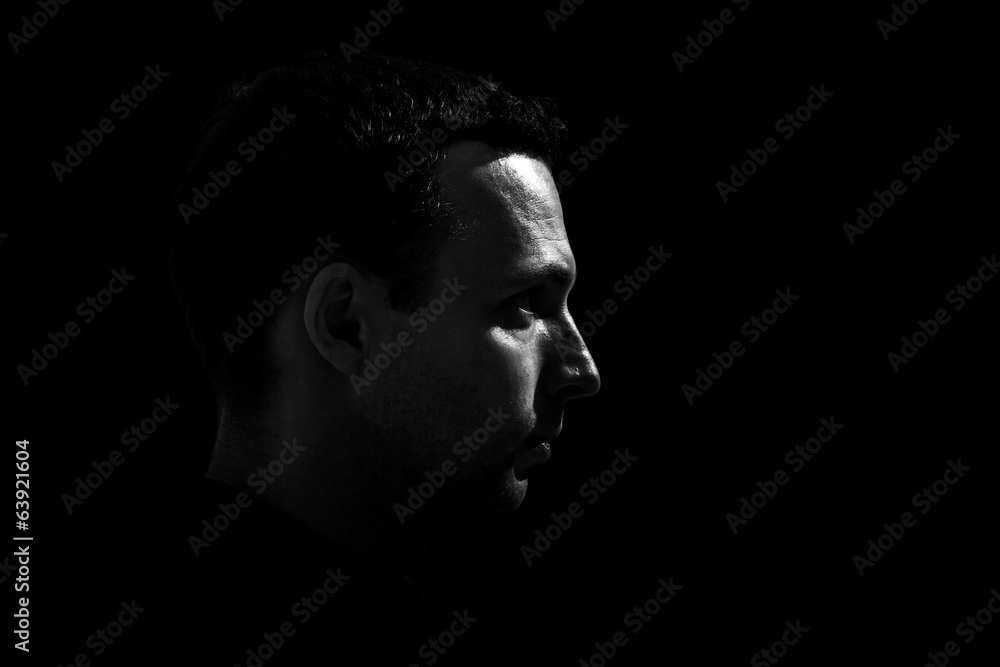Monochrome profile portrait of young Caucasian man on black back Monochrome profile portrait of young Caucasian man on black back