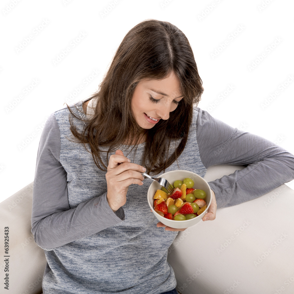 Beautiful woman relaxing on the sofa and eating a fruit salad Beautiful woman relaxing on the sofa and eating a fruit salad