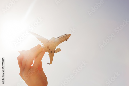 Airplane model in hand on sunny sky. Travel, transportation