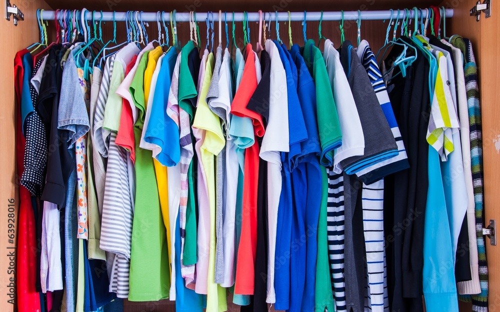 Colorful t-shirts hanging in wardrobe.