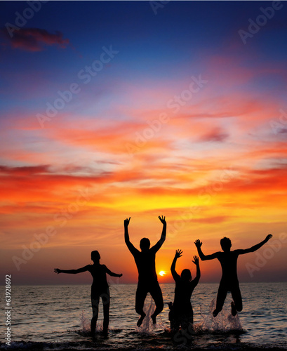 silhouette of jumping people on sunset background