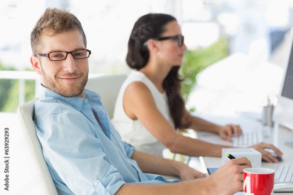 Obraz premium Handsome designer smiling at camera at desk