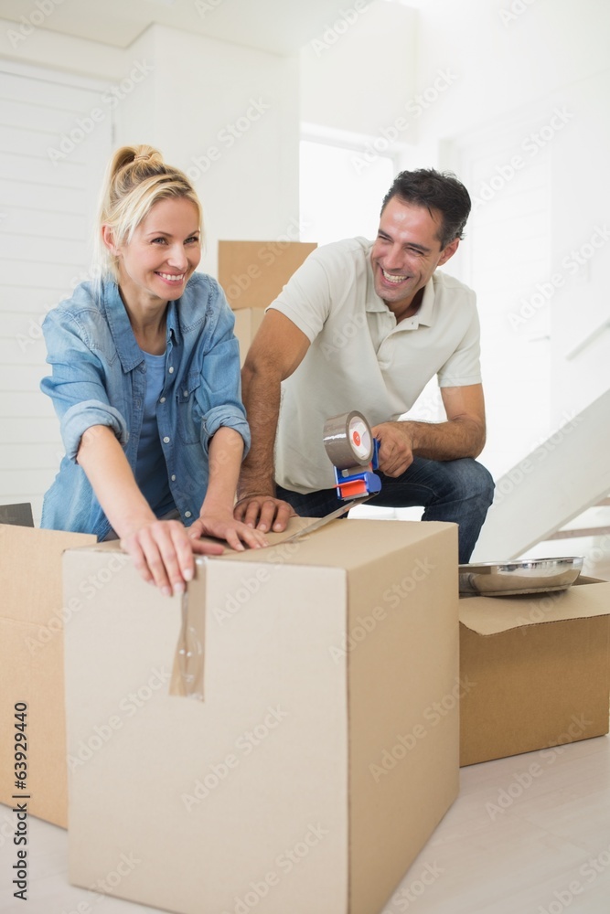 Smiling couple packing boxes in a new house Smiling couple packing boxes in a new house