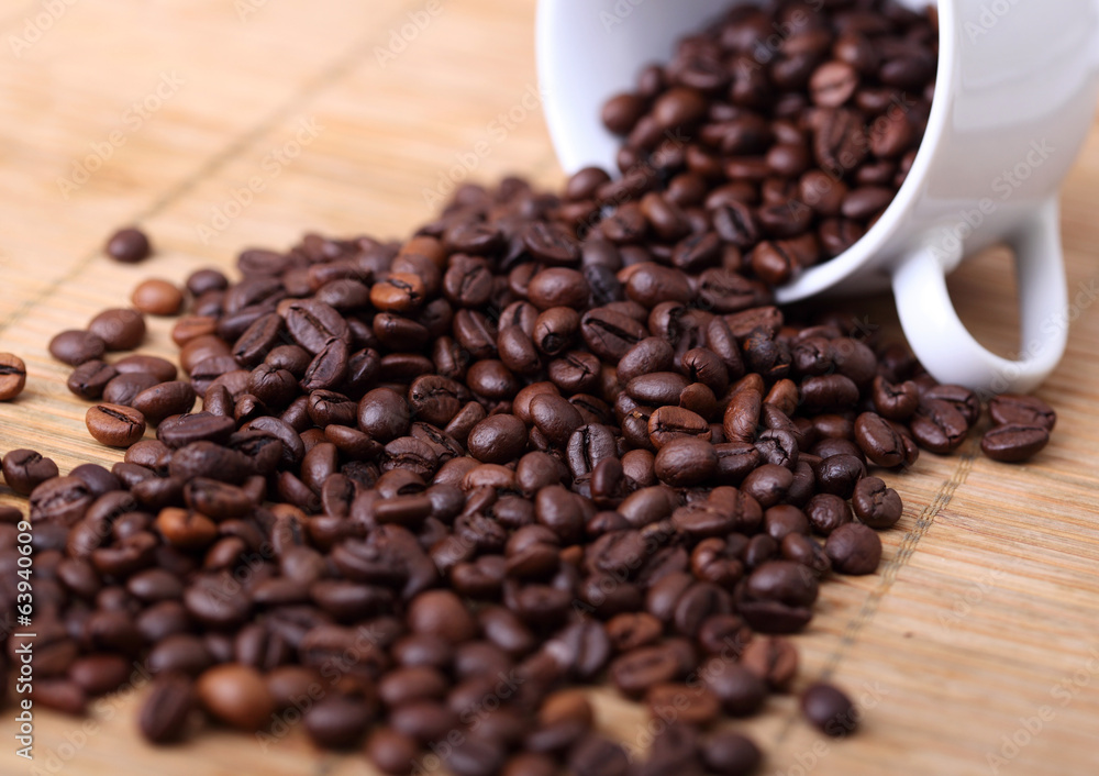 Fototapeta premium Coffee beans on a cup spilled