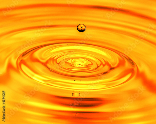 a drop of water falls in a golden water. macro