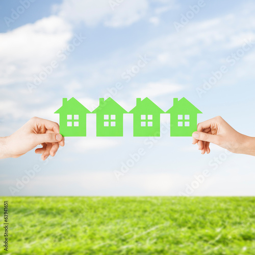 man and woman hands with many green paper houses