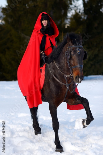beautiful woman with red cloak with horse outdoor in winter