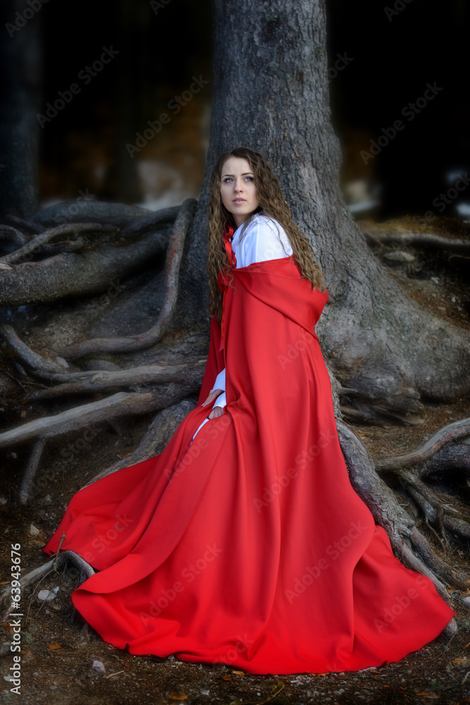 beautiful woman with red cloak posing in the woods
