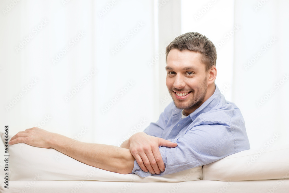 smiling man sitting on sofa at home smiling man sitting on sofa at home