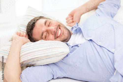 smiling young man lying on sofa at home