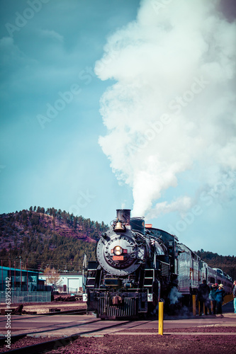 Old steam locomotive against blue cloudy sky, vintage train