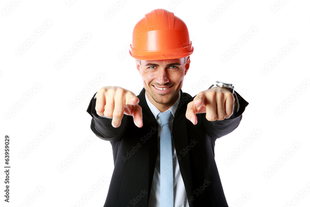 Happy businessman in hard hat pointing at you Happy businessman in hard hat pointing at you