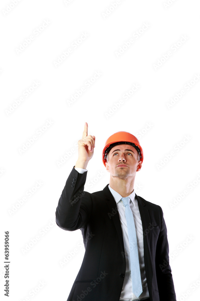 Portrait of a businessman in helmet pointing up at copyspace