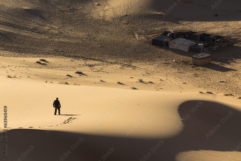 Fototapeta premium Man walking on dunes in desert