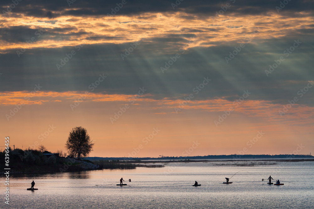 Fishermen on sunrise on the lake