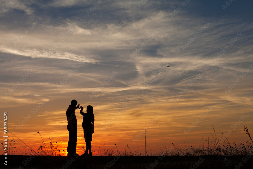 Silhouette of pregnant woman and a man in the sunset