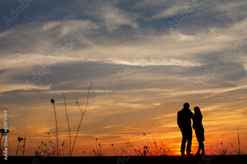 Silhouette of pregnant woman and a man in the sunset