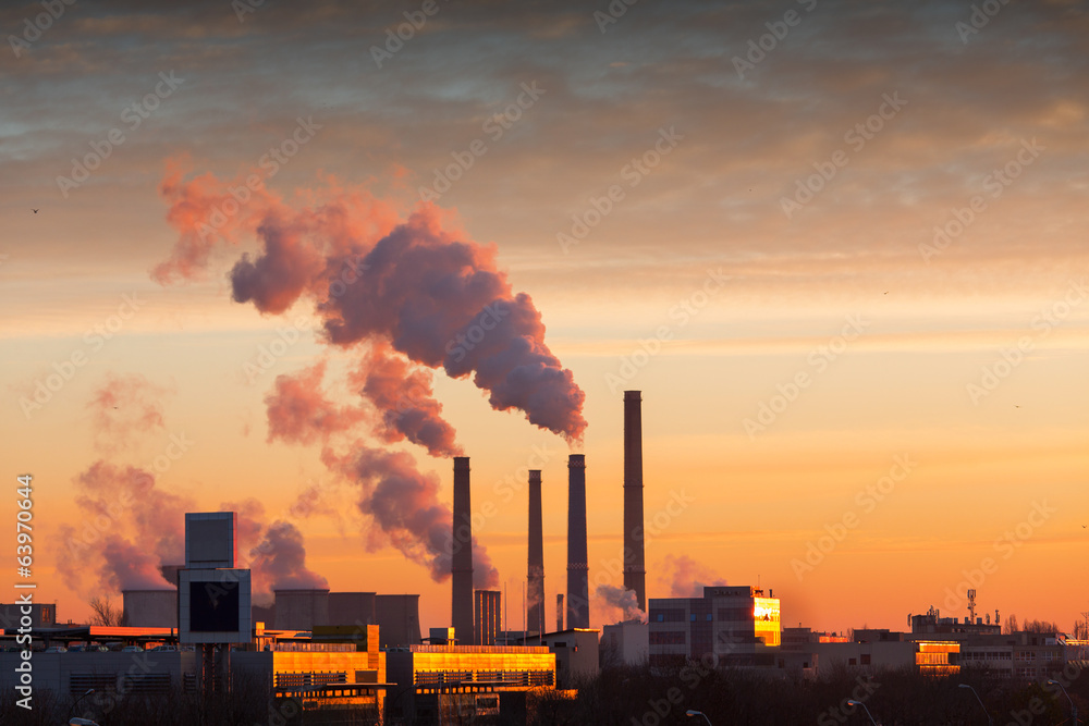 Winter scenic of power plant with a burning yellow sky behind