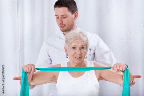 Physiotheraqpist assisting elderly woman in exercising