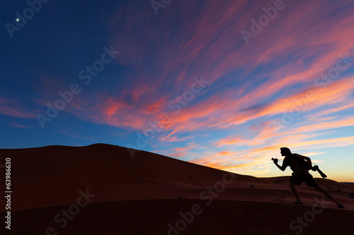 Photographers playing on dunes of desert Sahara at sunset, Moroc