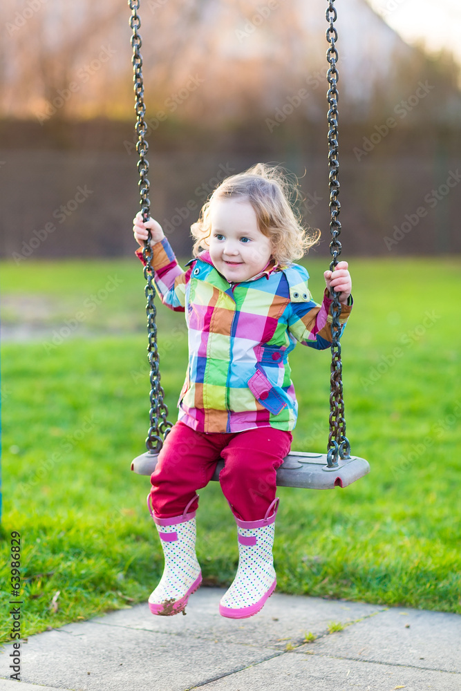 Happy laughing baby girl having fun on a swing in the garden Happy laughing baby girl having fun on a swing in the garden