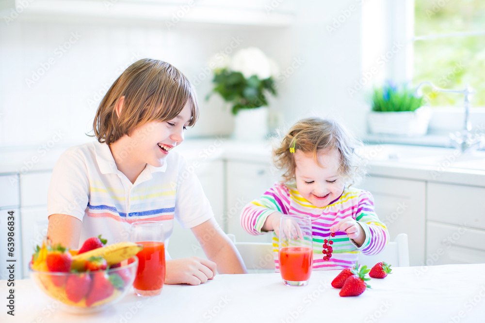 Happy teenager boy and his cute toddler sister having fruit Happy teenager boy and his cute toddler sister having fruit
