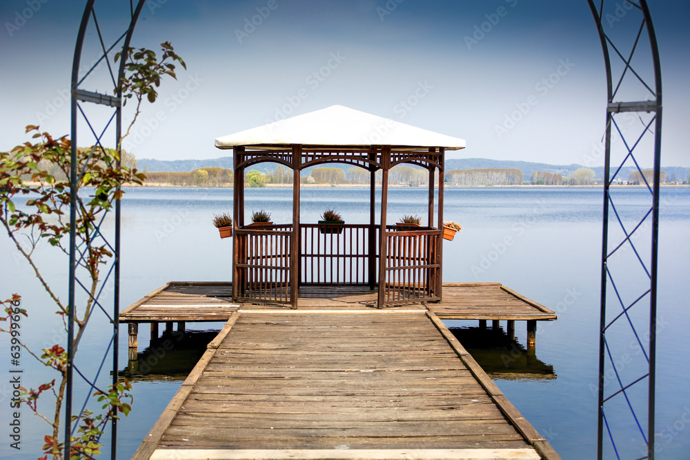 Wooden gazebo on dock over peaceful lake