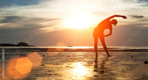Woman silhouette exercise on the beach at sunset. © De Visu