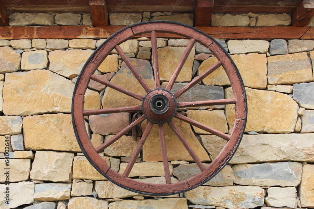 Old decorative wheel on stone wall