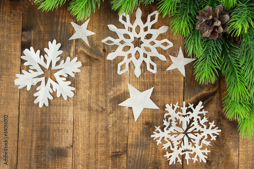 Beautiful paper snowflakes with fir branch on wooden background