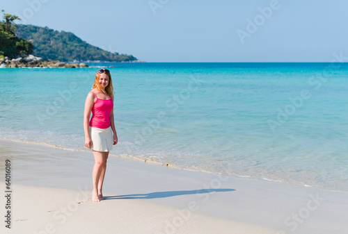 Young woman in pink top and beige skirt walking on beach © Valeri Luzina