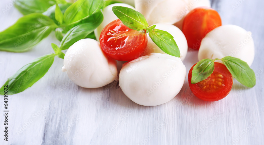 Tasty mozzarella cheese with basil and tomatoes, on wooden Tasty mozzarella cheese with basil and tomatoes, on wooden