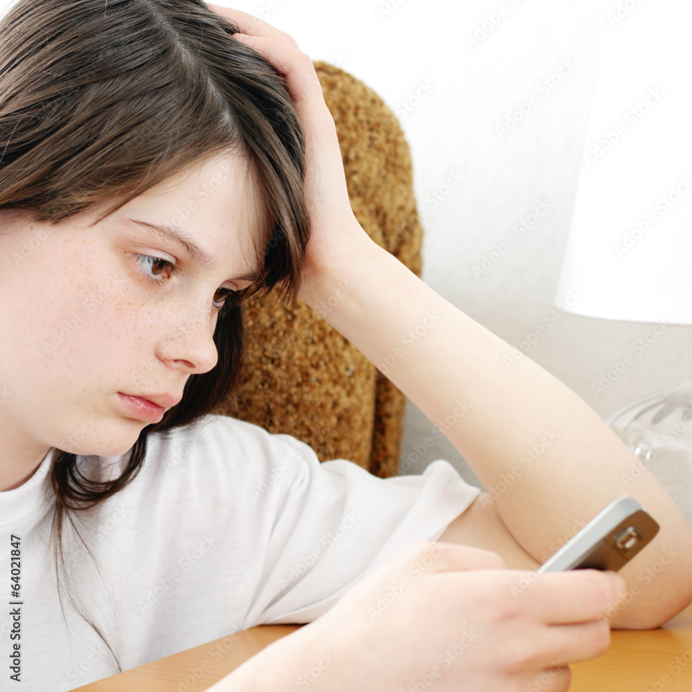 Naklejka premium Sad Teenage Girl with Cellphone