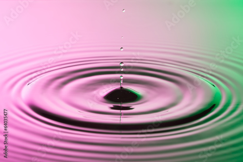 Water drop close up with concentric ripples colourful pink and g