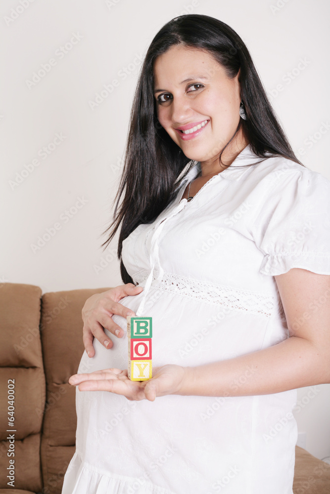 Beautiful hispanic pregnant woman having the word boy with woode Beautiful hispanic pregnant woman having the word boy with woode