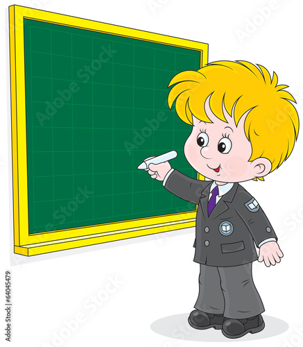 Schoolboy writes with chalk on the blackboard