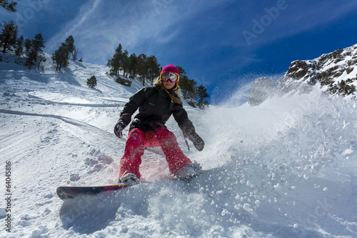Woman snowboarder in motion in mountains photo