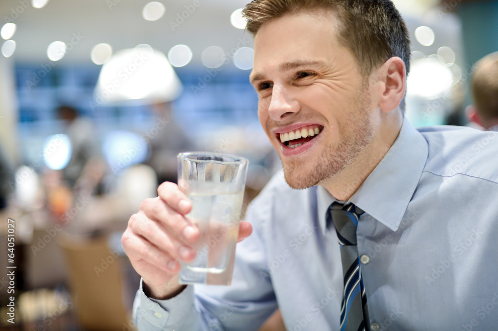 Smiling young man drinking water in cafe Smiling young man drinking water in cafe
