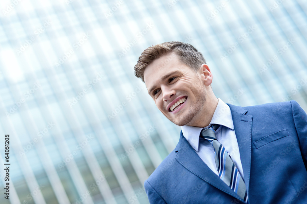 Young smiling man on modern building background Young smiling man on modern building background