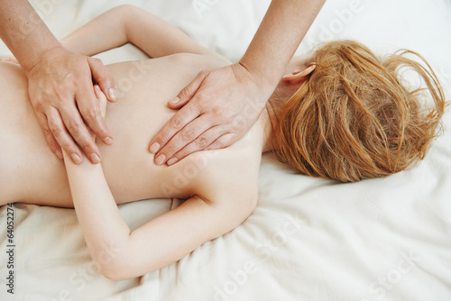 Masseur massaging a child back