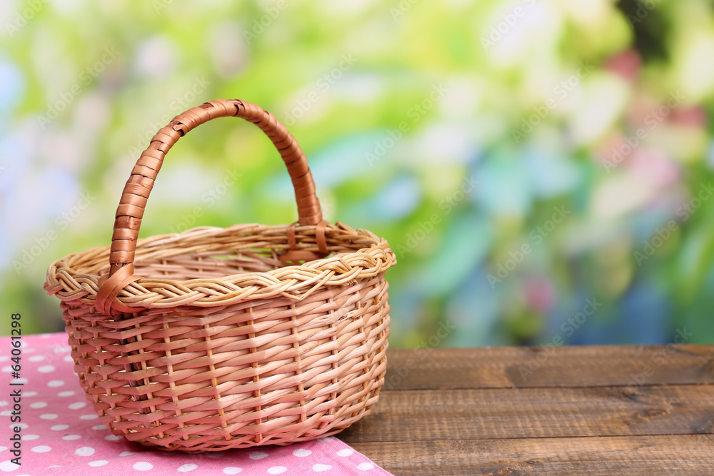 Empty wicker basket on wooden table, on bright background Empty wicker basket on wooden table, on bright background