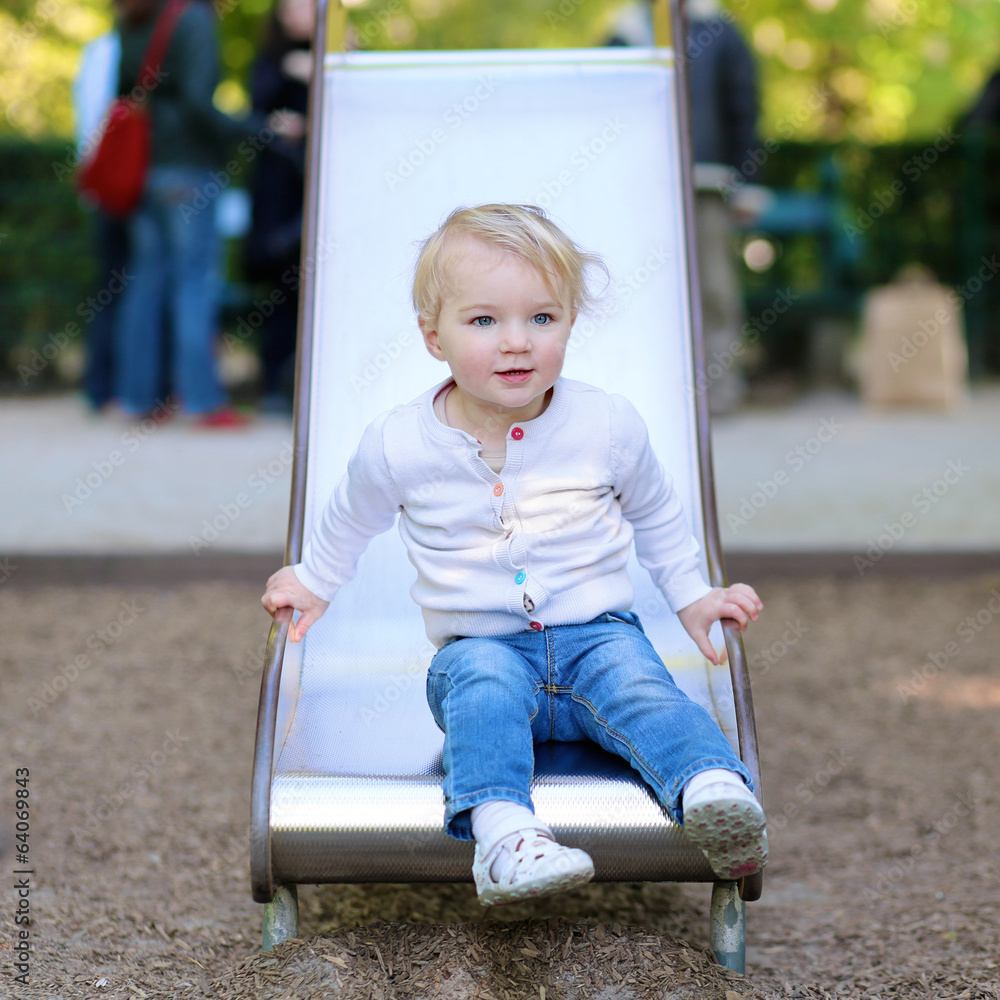 Happy toddler girl playing in the park on the slide Happy toddler girl playing in the park on the slide