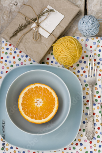 Juicy orange on blue plate is the old pad and tangles of yarn